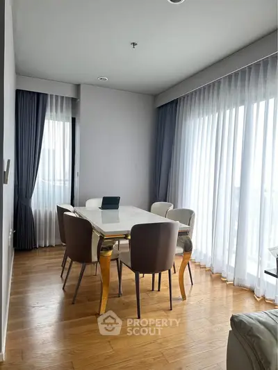 Elegant dining area with modern table and chairs, surrounded by floor-to-ceiling windows and curtains.