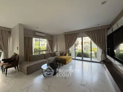 Spacious living room with modern decor and large windows offering garden views.