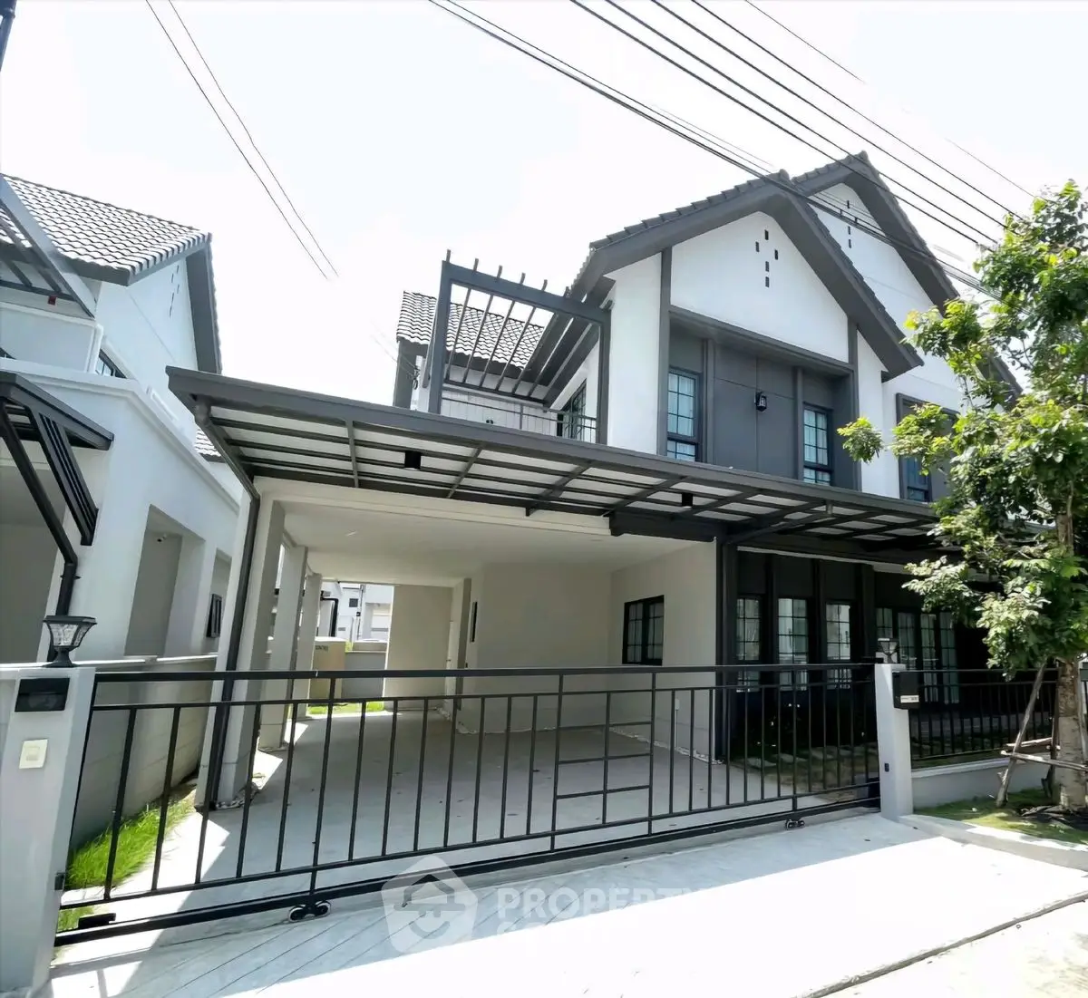 Modern two-story house with spacious driveway and sleek metal gate in a suburban neighborhood.