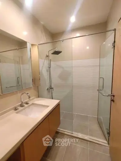 Modern bathroom with glass shower enclosure and sleek vanity in a contemporary home.