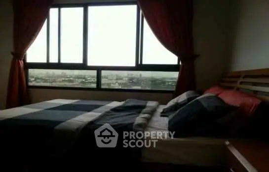 Cozy bedroom with city view and large window, perfect for relaxation.