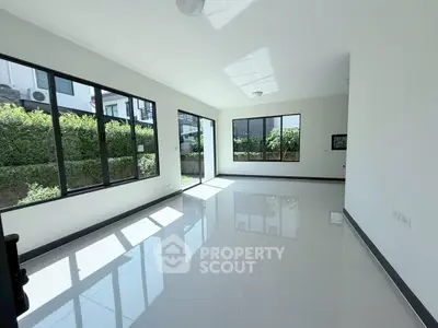 Spacious modern living room with large windows and garden view, perfect for natural light lovers.