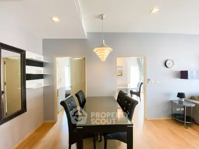 Modern dining area with sleek black table and chairs, adjacent to cozy living room in stylish apartment.