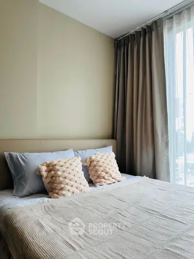 Cozy bedroom with plush pillows and large window offering natural light