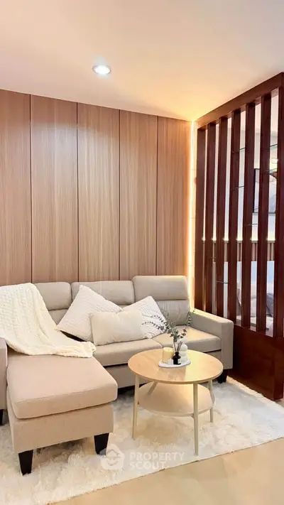 Modern living room with cozy beige sofa, wooden paneling, and stylish decor.