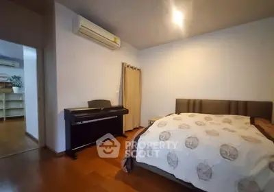 Cozy bedroom with wooden flooring and piano, featuring modern air conditioning.
