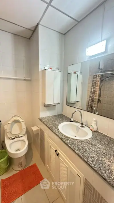 Modern bathroom with granite countertop and white fixtures in a stylish apartment.