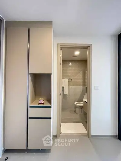 Modern bathroom with sleek design and neutral tones, featuring a compact layout and contemporary fixtures.