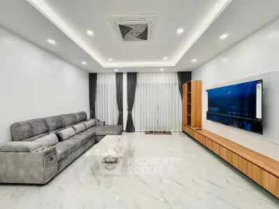 Spacious modern living room with sleek furniture and large TV, perfect for entertainment.