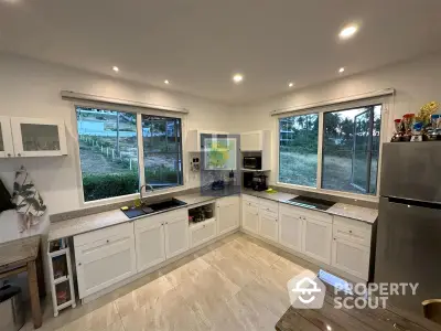 Spacious kitchen with modern appliances, ample cabinetry, and large windows offering natural light and a serene view of the outdoors.