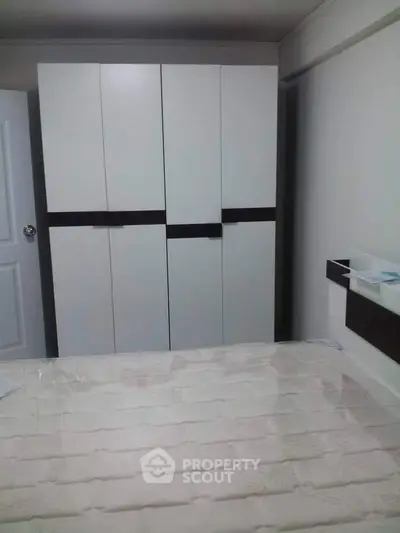 Modern bedroom with sleek white wardrobe and cozy bed setup.