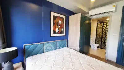 Modern bedroom with blue accent wall, stylish artwork, and ensuite bathroom.