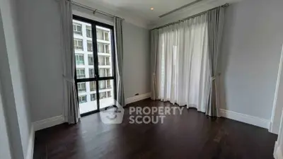 Spacious empty room with dark wood flooring and large windows in modern apartment.