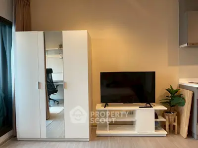 Modern living room with sleek white wardrobe and TV stand, featuring a cozy workspace and stylish decor.