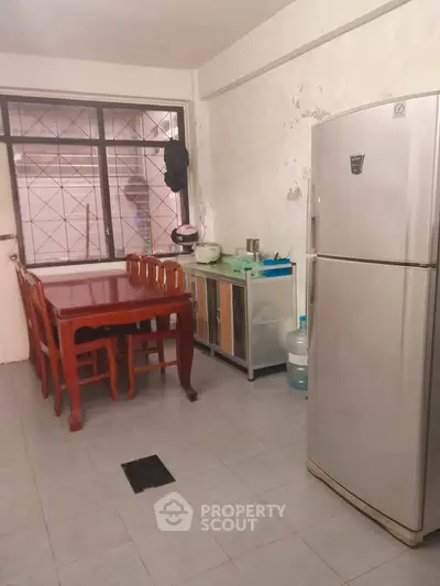 Cozy kitchen with dining table and fridge, ideal for family meals.