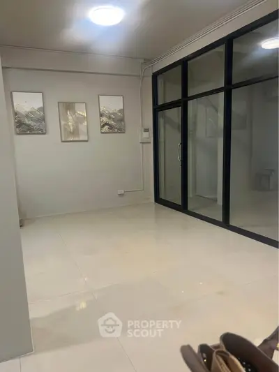 Spacious modern room with glass doors and elegant wall art, perfect for versatile living or office space.
