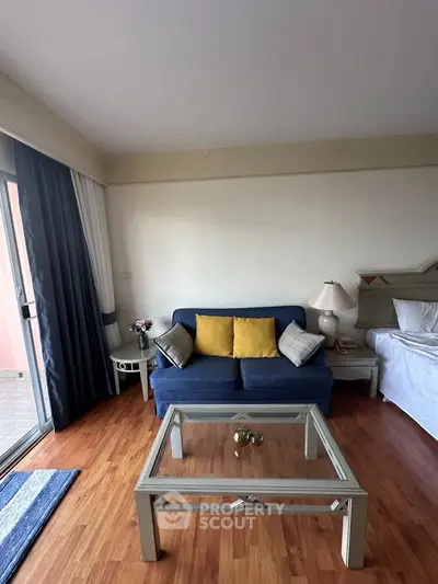 Charming living room with cozy blue sofa, glass coffee table, and elegant decor, perfect for relaxation.