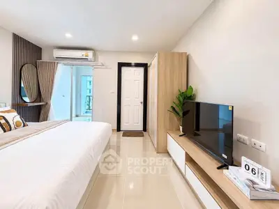 Modern bedroom with sleek furniture and natural light, featuring a TV and air conditioning.