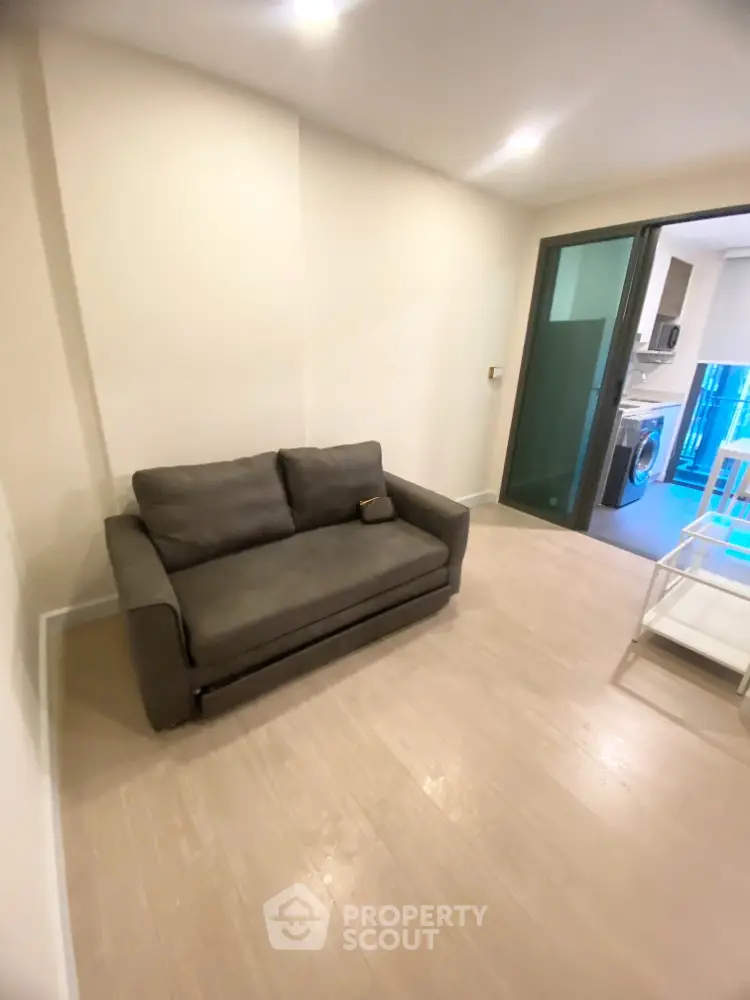 Modern living room with cozy sofa and view into sleek kitchen area