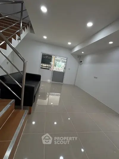 Spacious modern living room with sleek staircase and glossy tiled flooring