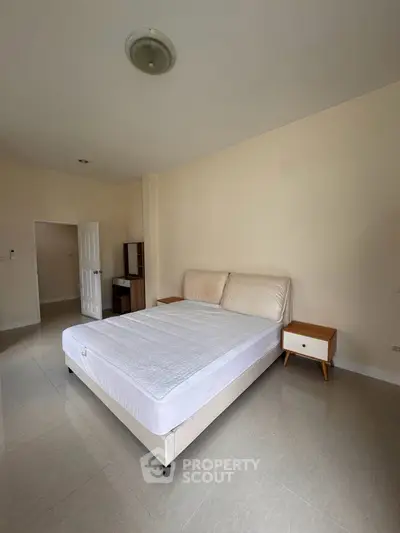 Spacious bedroom with minimalist design and natural light, featuring a comfortable bed and modern furnishings.