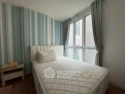 Cozy bedroom with striped wallpaper and large window for natural light.