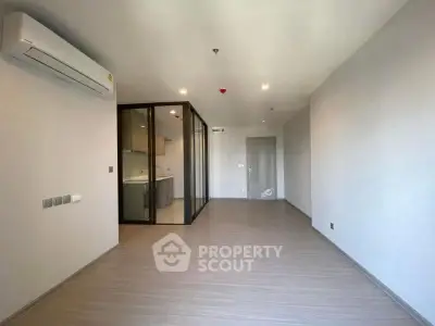 Spacious modern living room with air conditioning and glass partition leading to kitchen.