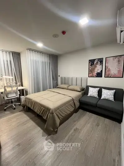 Modern bedroom with stylish decor, featuring a cozy bed, sleek sofa, and a functional study area.