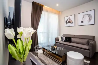 Modern living room with stylish decor and large window, featuring a cozy sofa and elegant tulip arrangement.