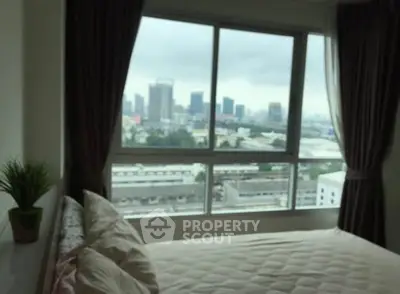 Cozy bedroom with city view through large window, perfect for urban living.