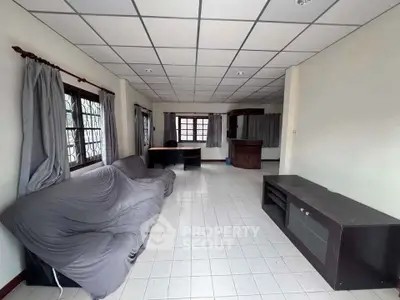 Spacious living room with tiled floor and large windows, featuring a cozy sofa and entertainment unit.