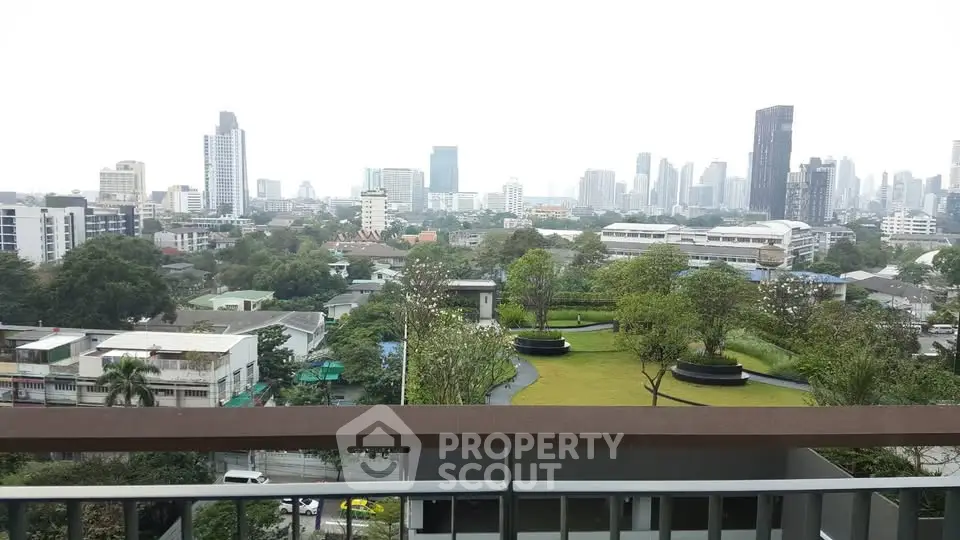 Stunning cityscape view from a high-rise balcony overlooking lush green gardens and urban skyline.