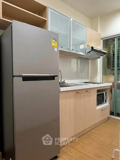 Modern kitchen with stainless steel fridge and wooden cabinets in a cozy apartment.