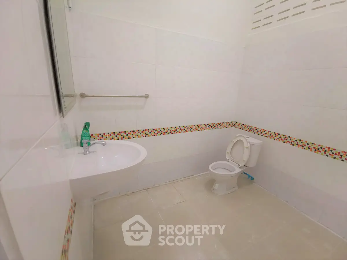 Spacious bathroom with modern fixtures and colorful tile accents.