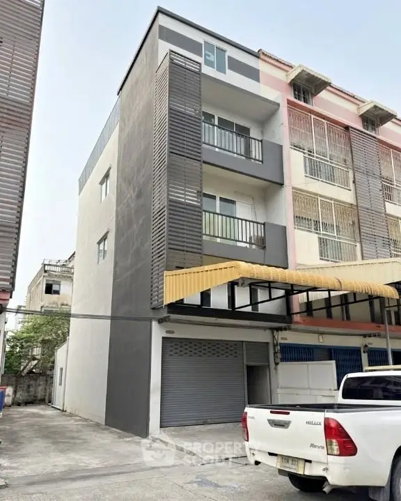 Modern multi-story building with sleek design and parking area in urban setting.