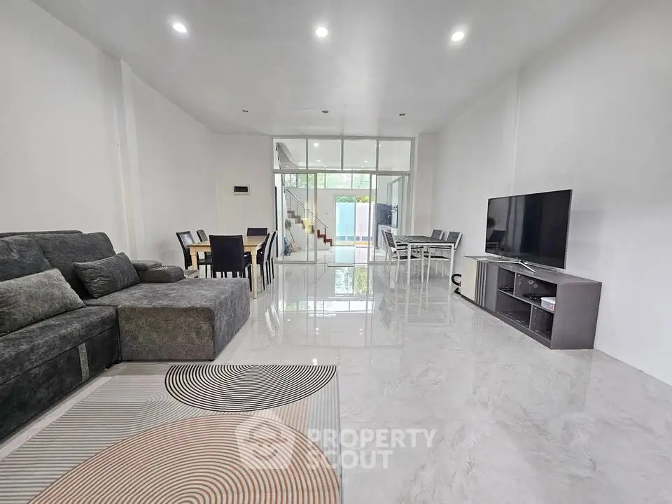 Spacious modern living room with sleek furniture and large TV, ideal for family gatherings.
