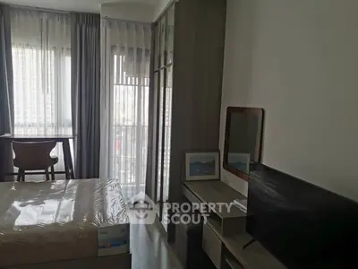 Modern bedroom with natural light, stylish furniture, and a sleek TV setup.
