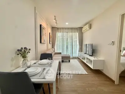 Modern living room with stylish decor and natural light, featuring a cozy dining area and sleek entertainment setup.