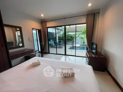 Luxurious bedroom with pool view and modern furnishings in a tropical setting.