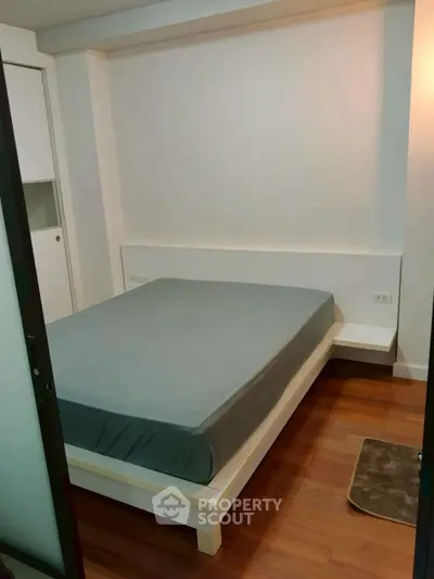 Cozy minimalist bedroom with wooden flooring and modern bed frame.