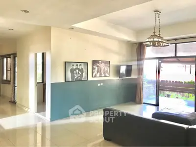 Spacious living room with large windows and modern decor, perfect for relaxation and entertainment.
