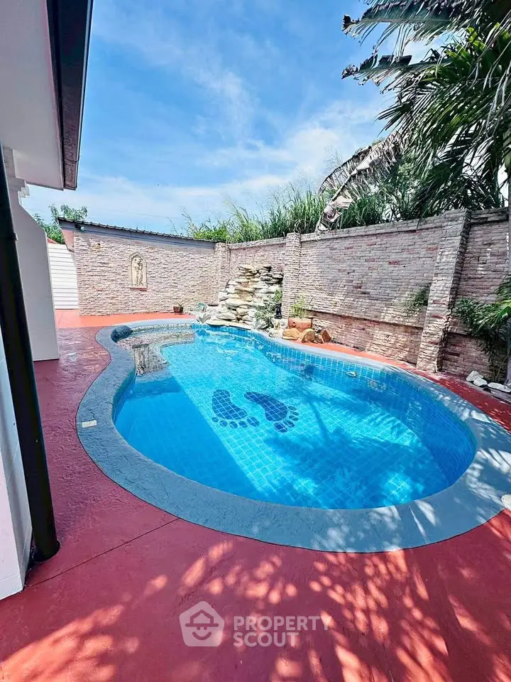 Charming backyard pool with unique footprint design and lush greenery.