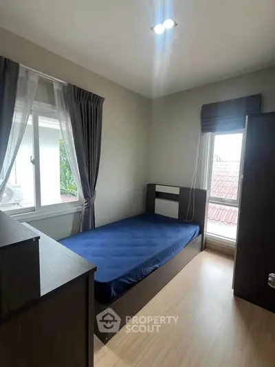 Cozy bedroom with single bed and large window offering natural light