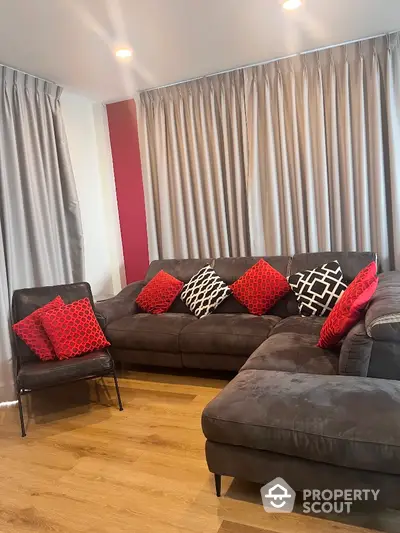 Stylish living room with modern gray sofa and vibrant red cushions, perfect for relaxation.