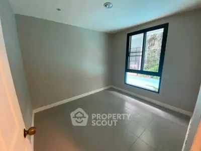Spacious empty room with large window and neutral tones, perfect for customization.