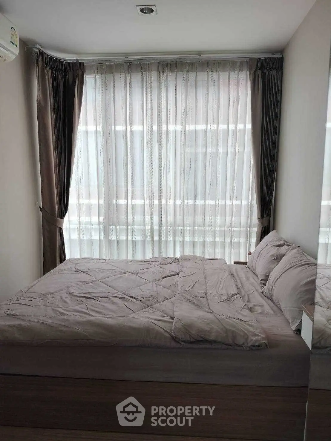 Cozy bedroom with large window and elegant curtains, perfect for relaxation and comfort.