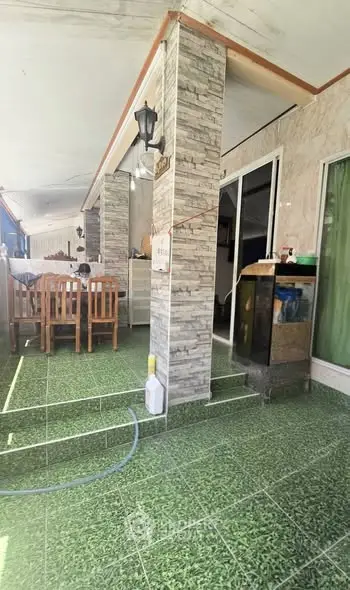 Charming outdoor patio with dining area and green tiled flooring.