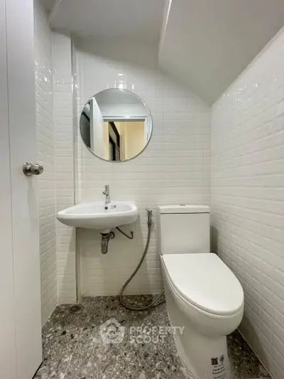 Modern compact bathroom with white tiles and round mirror