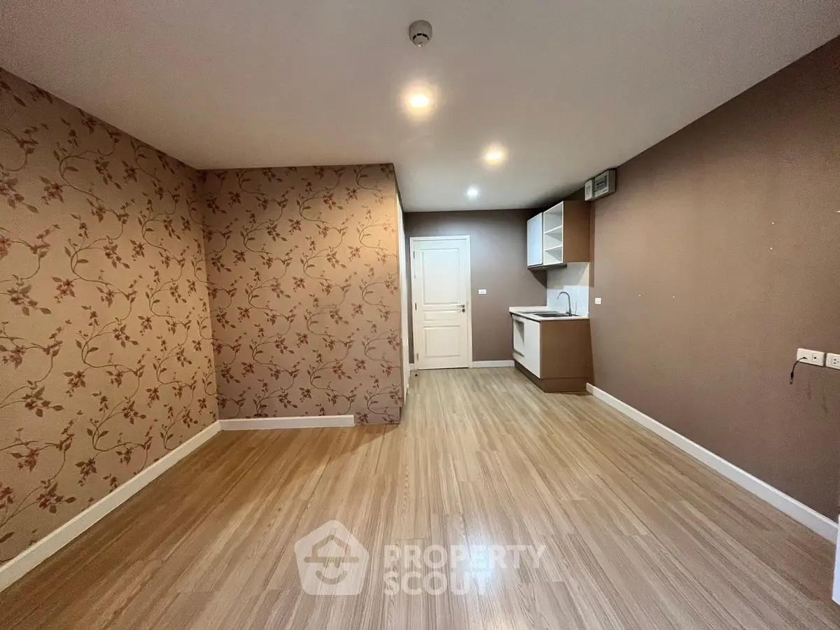 Spacious living room with elegant floral wallpaper and modern kitchen corner