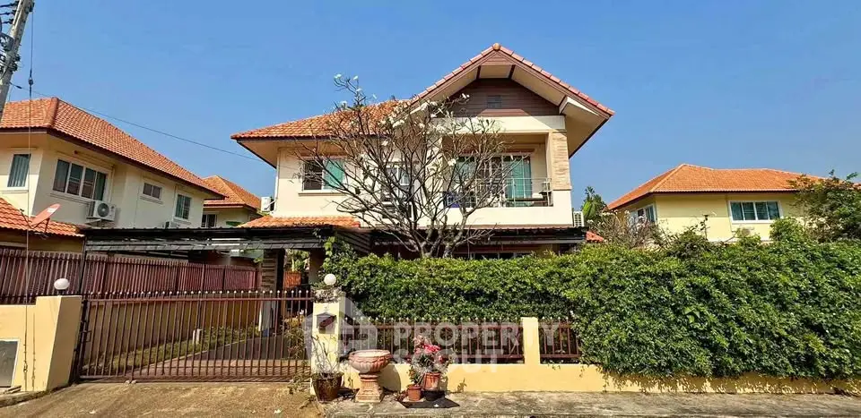 Charming two-story house with red-tiled roof and lush garden in a serene neighborhood.